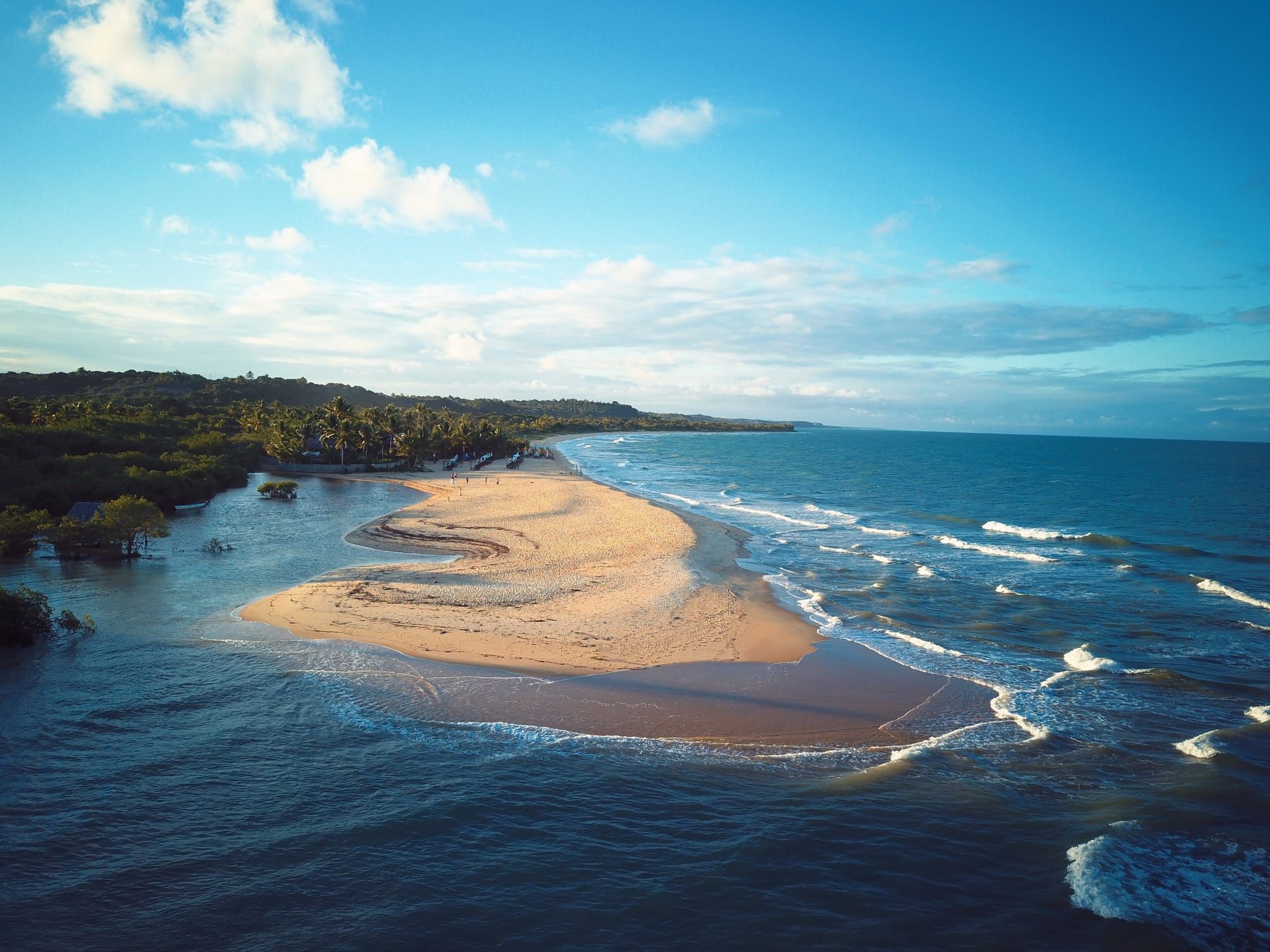 Vista aérea de uma foz de rio com banco de areia e mar azul na APA Caraíva/Trancoso