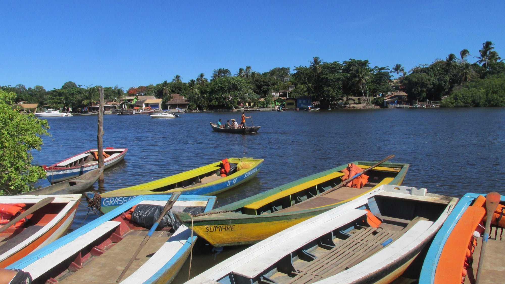 Canoas coloridas atracadas na margem do Rio Caraíva, com a vila ao fundo