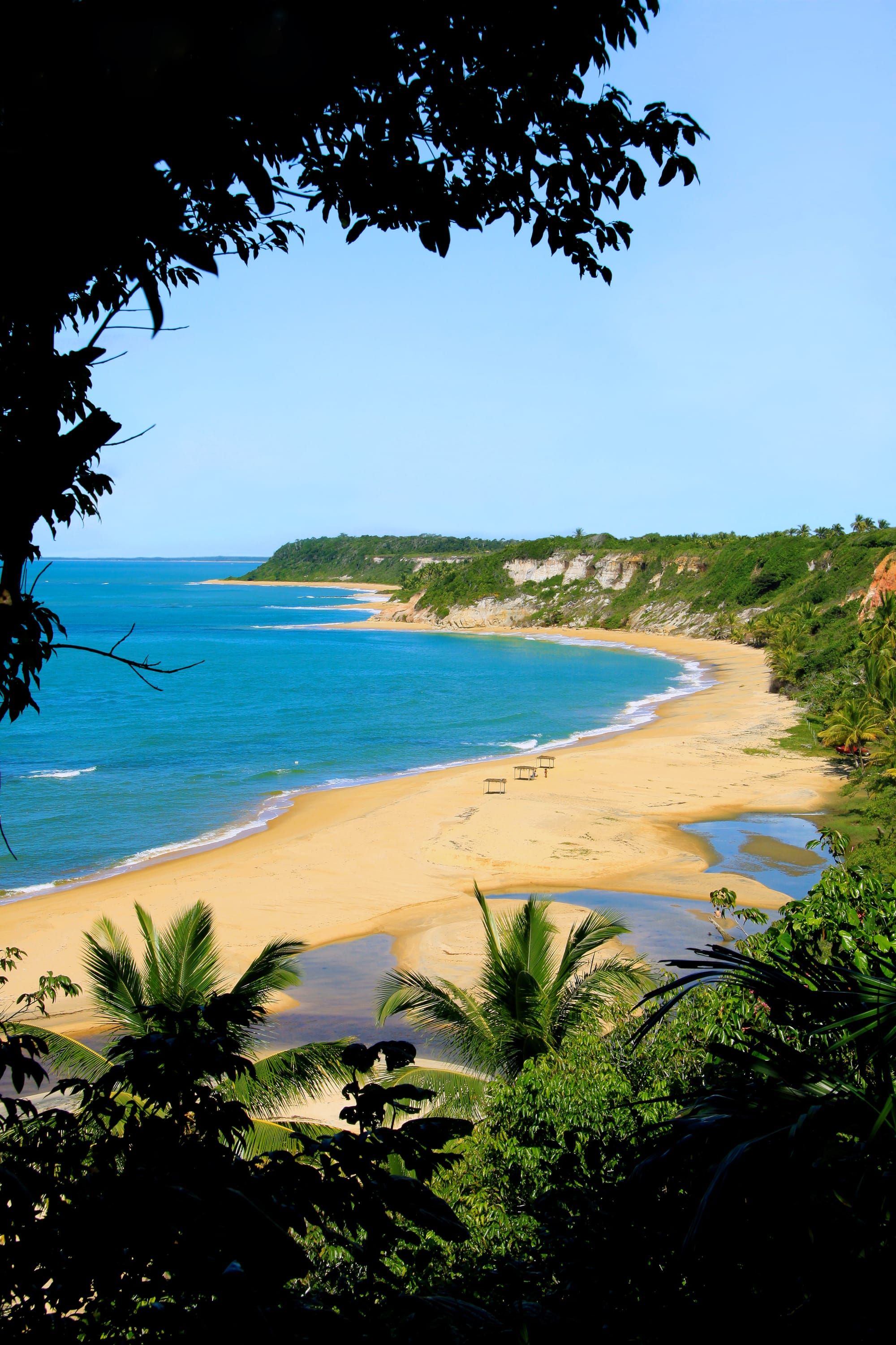 Enseada da Praia do Espelho vista do alto, com falésias, mata e o mar azul